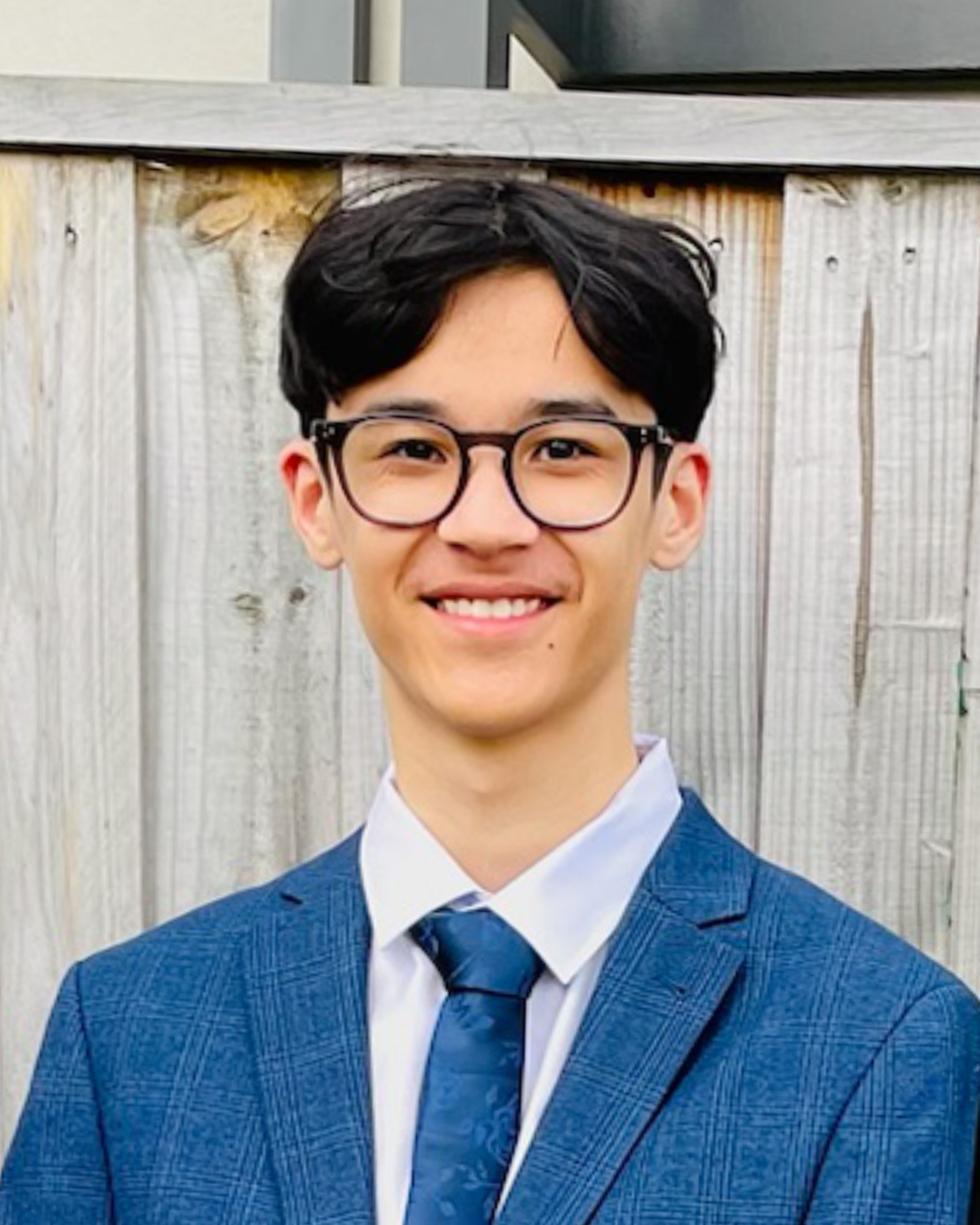 Headshot image of Aidan Kalaitzakis wearing a blue suit and tie.